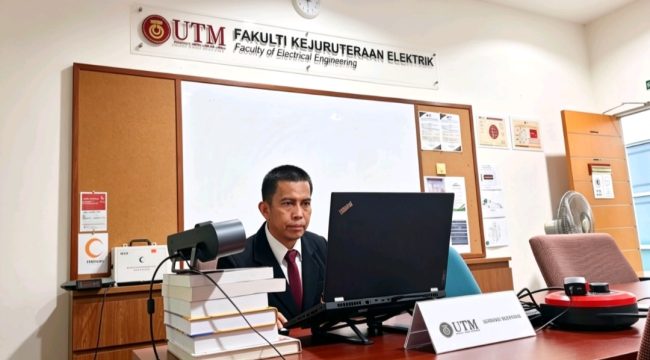 Sofyan ST MT memaparkan hasil disertasinya tentang pengaruh harmonik Solar Photovoltaic terhadap kestabilan tegangan jaringan distribusi saat menjalani ujian doktoral di hadapan tim pembimbing dan penguji di University Teknologi Malaysia (UTM). Johor Bahru, Malaysia, Jumat (12/6/2026) (Foto: Humas)